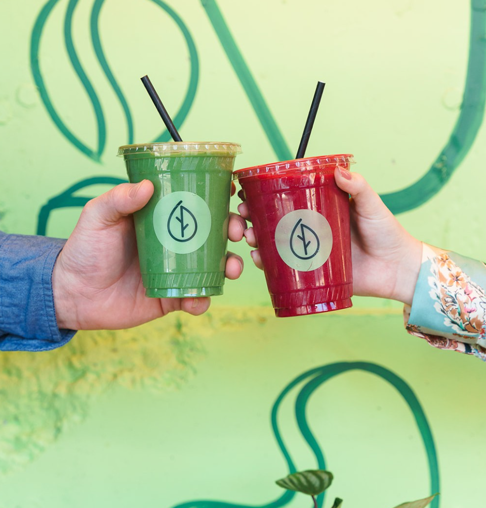 two people cheers'ing frozen superfood smoothies in plastic branded cups representing food service partnerships