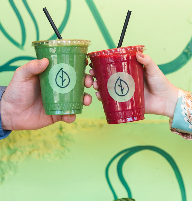 two people cheers'ing frozen superfood smoothies in plastic branded cups representing food service partnerships