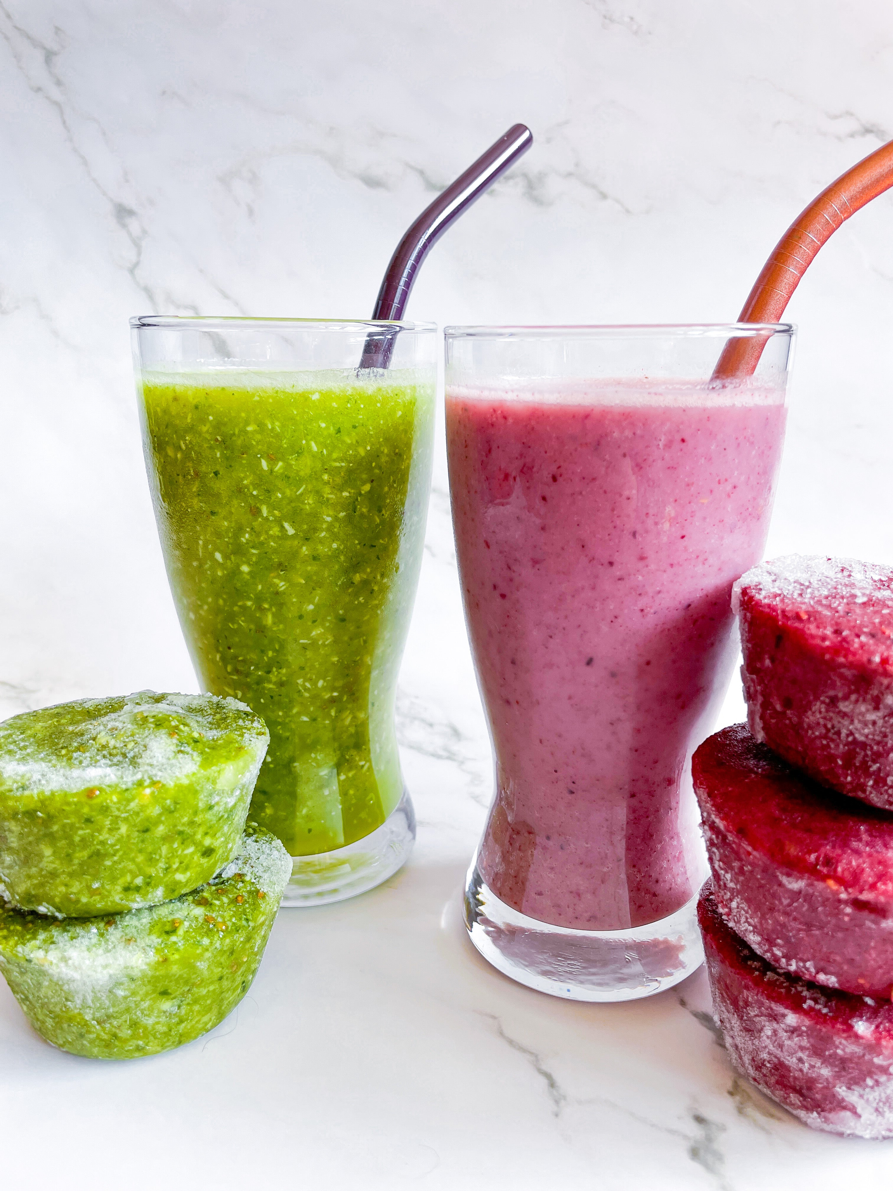 two glasses of Nutes frozen superfood smoothies with green and red pucks
